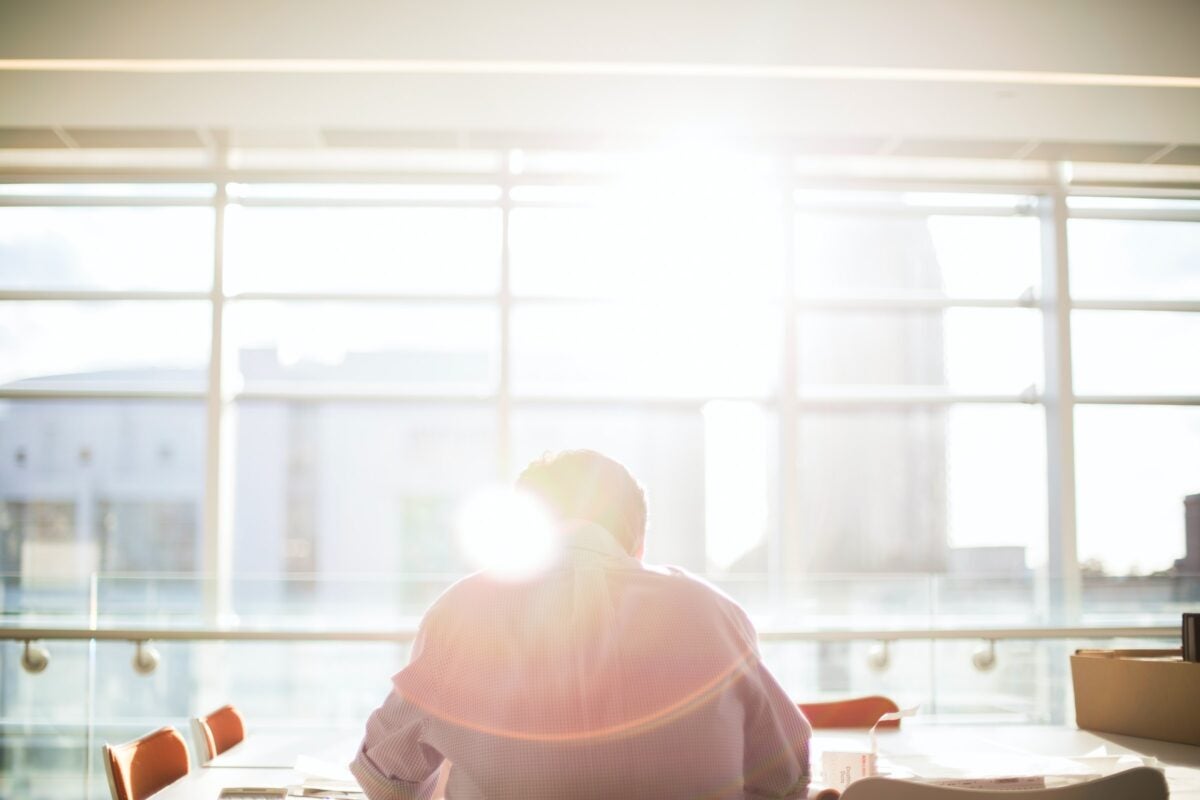 A picture of a student sitting at a conference table with their back turned towards the camera